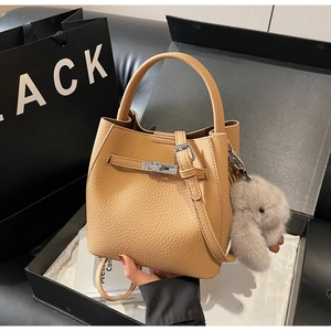 Dettaglio borsa a secchiello beige texture litchi con lucchetto e ciondolo a coniglio
