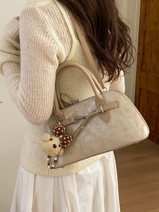 Vintage matte cream Boston bag with bear charm and adjustable shoulder strap worn by model