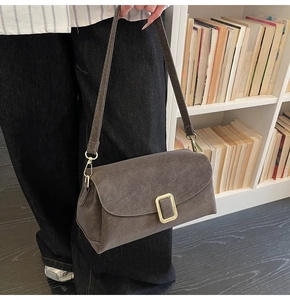Detail shot of a matte dark grey retro square bag with golden metallic buckle closure
