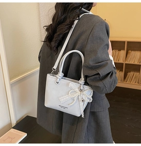 Détail du sac seau en cuir texturé avec nœud en dentelle et pampille de perles