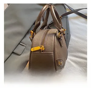 Detail showing high-quality gold zipper pull and rivet on textured brown leather bag