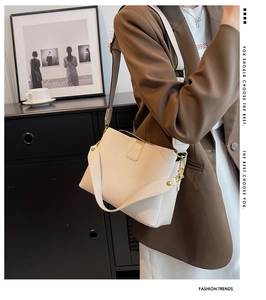 Detail shot of beige pebble leather bucket bag with gold hardware and wide shoulder strap