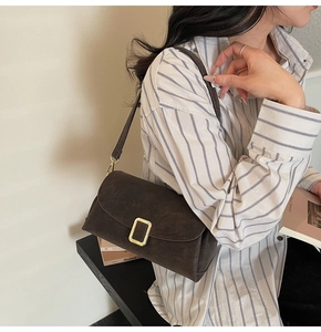 Macro view of retro dark brown suede crossbody bag with elegant gold square buckle