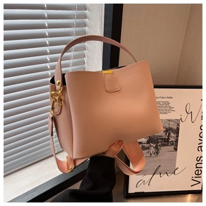 Détail d'un sac seau en cuir litchi rose avec finitions dorées et large bandoulière