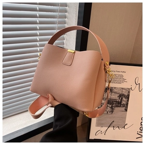 Détail du sac seau rose en cuir grainé avec bandoulière large et boucle métallique