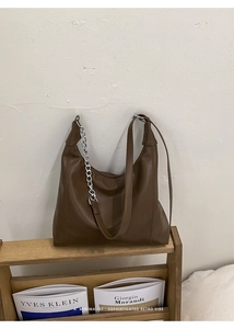 Detail of dark brown leather tote bag with silver chain strap and minimalist hobo design