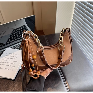 Detail of retro brown half-moon bag featuring matte leather texture and gold chain strap
