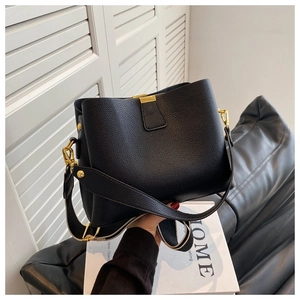 Detail of black litchi grain leather bucket bag with gold metal clasp and wide strap