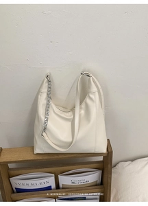 Detail of white moon hobo bag with silver chain on a wooden magazine rack