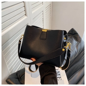 Détails du sac seau en cuir grainé noir avec boucles dorées et bandoulière large