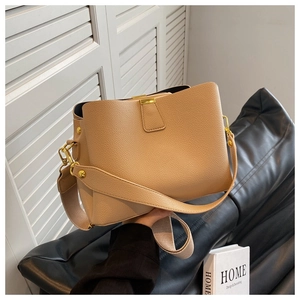 Détail du sac seau en cuir grainé beige avec large bandoulière et fermoir magnétique doré