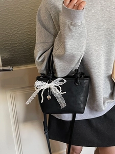 Sac seau noir chic avec nœud en dentelle et chaîne perlée porté avec tenue décontractée