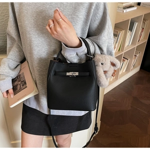 Dettaglio borsa a secchiello in pelle martellata nera con chiusura in metallo e charm