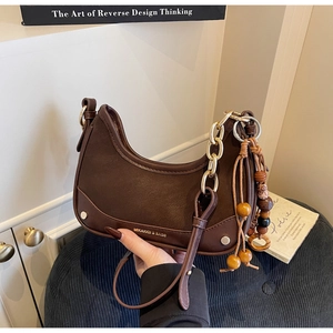 Détails du sac demi-lune marron avec chaîne dorée et pompon en perles de bois