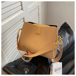 Detail of beige litchi grain bucket bag with gold hardware and wide shoulder strap
