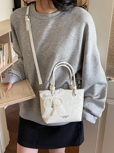 Sac seau élégant blanc crème avec dentelle, nœud et breloque perle sur un mannequin