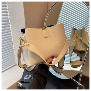 Détail du sac seau en cuir grainé blanc crème avec boucles dorées et large bandoulière
