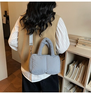 Detail of grey quilted puffer bag with wide strap worn by a model in lifestyle setting