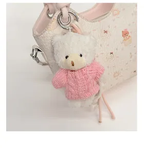 Detailed view of a plush bear charm with pink sweater on a printed bucket bag