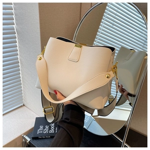 Détail du sac seau en cuir blanc cassé avec boucles dorées et bandoulière large en toile