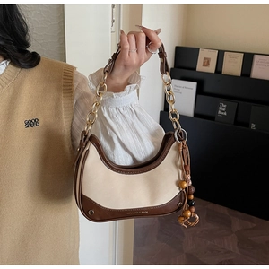 Detailed close-up of khaki and brown hobo bag with gold chain and beaded tassel charm