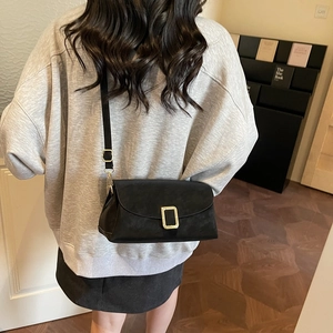 Classic black leather crossbody bag with golden buckle shown in a lifestyle indoor setting