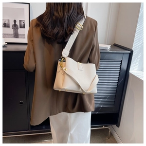 Détail du sac seau en cuir grainé blanc cassé avec bandoulière large et boucles dorées