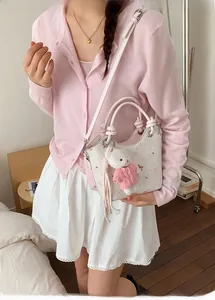 Detail of cream bucket bag with cute bear charm and pink lining on shoulder strap