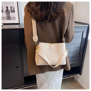 Détail du sac seau crème en cuir à motif litchi avec des finitions métalliques dorées