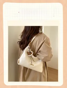 Detail of creamy white leather tote bag with gold logo and horse charm on shoulder
