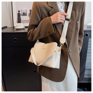 Détail du sac seau en cuir grainé blanc cassé avec bandoulière tissée et boucles dorées