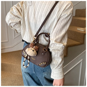 Sac oreiller en cuir marron foncé avec anse perle et ours peluche sur escalier