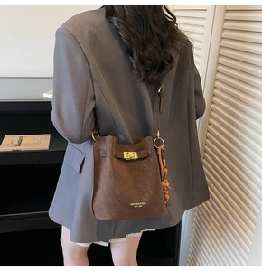 Detailed shot of brown suede bucket bag with gold twist lock and wooden bead accessory