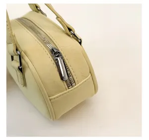 Detail of cream leather boston bag showing polished silver zipper and precise stitching