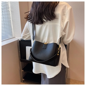 Vue arrière d'un sac seau noir en cuir grainé porté en bandoulière sur un mannequin