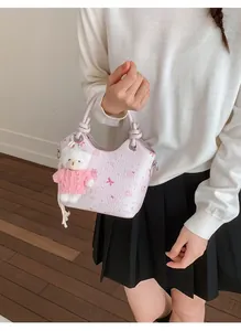 Detail of pink crossbody bucket bag with bear print and plush charm on a model