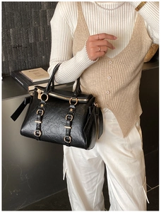 Detail view of black tote bag with wrinkled texture and golden hardware accents