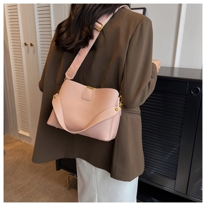 Détail du sac seau en cuir rose à motif litchi avec boucle dorée et bandoulière large