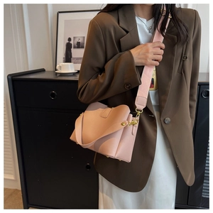 Sac seau rose poudré avec texture litchi porté par un mannequin dans un bureau chic