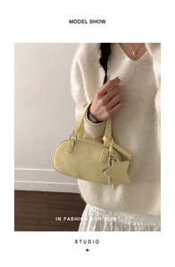 Detail of light yellow Boston bag with leather texture and a star pendant on handle