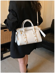 Detail showing white pleated faux leather tote bag with gold hardware on a shoulder
