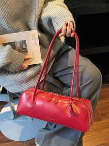 Sac baguette minimaliste en cuir rouge avec longues anses porté par un mannequin femme