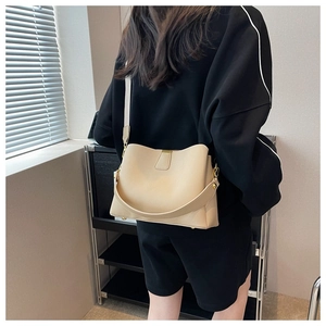 Détail du sac seau crème montrant le cuir grainé et les ferrures dorées portées par le modèle