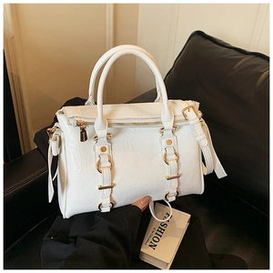 Detail of white glossy tote bag showing gold metal buckles and pleated leather texture