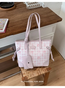 Detail of pink plaid tote bag with cat patterns and matching mini pouch on a stool