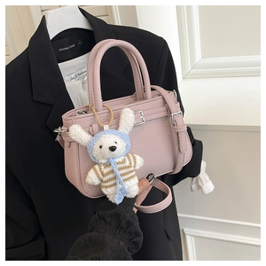 Dettaglio della borsa a secchiello in pelle rosa con un grazioso ciondolo a coniglietto