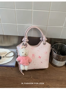 Detailed shot of a pink tote bag with cat patterns and a teddy bear plush charm