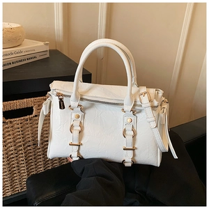 Close-up of white tote bag with pleated texture, gold hardware and adjustable strap