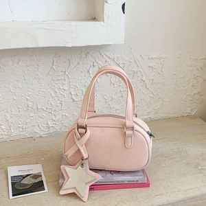 Detail of light pink mini Boston bag with double handles and a silver star pendant
