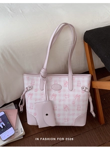 Detail of pink cat-printed tote bag with matching coin purse on a wooden chair